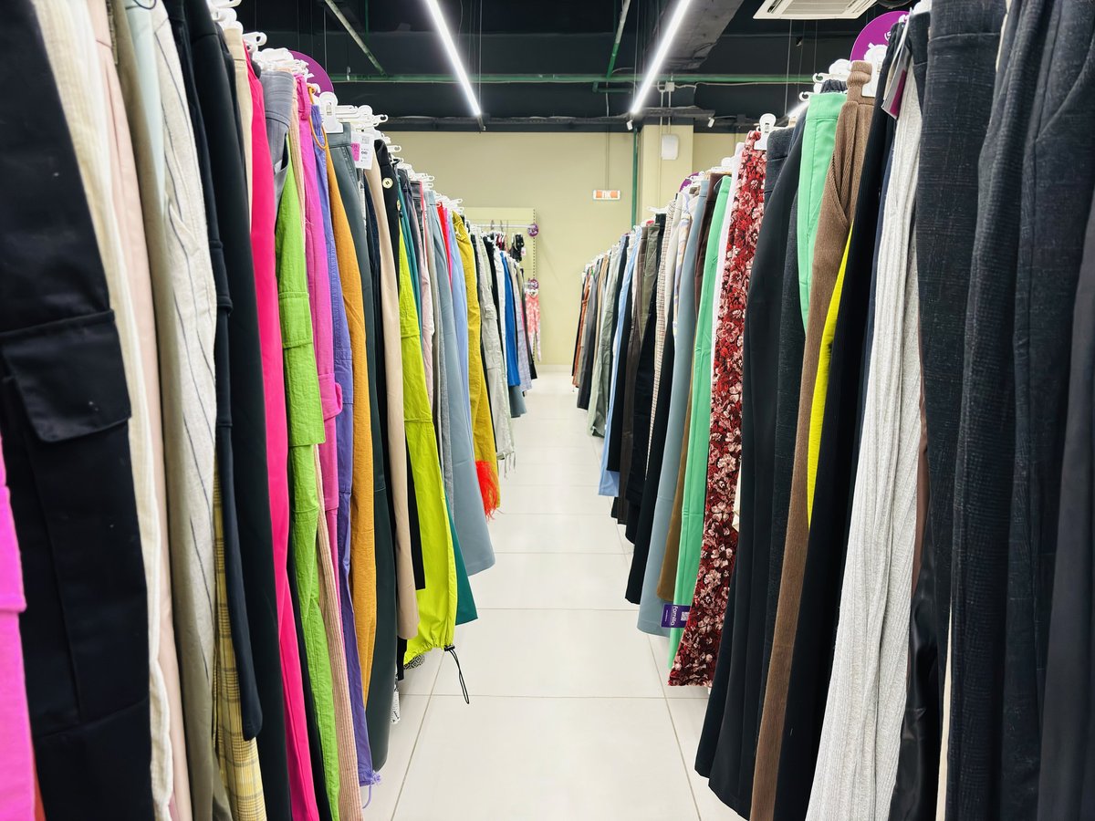 Colorful pants on hangers on rails in a secondhand store