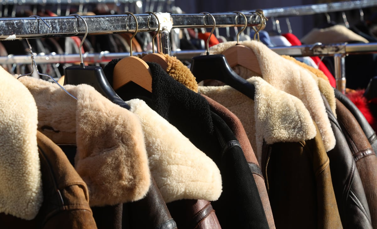 Rows of colorful used clothing for sale at a market stall