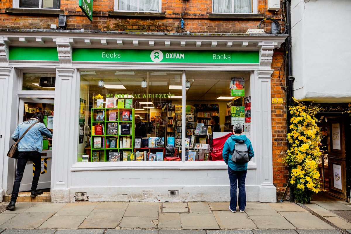 Shoppers outside a charity bookstore looking at the window display